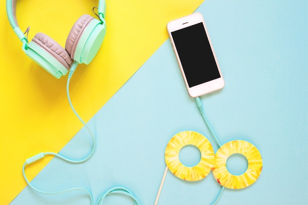 Creative flat lay of summer concept with smart phone and headphones on colour background