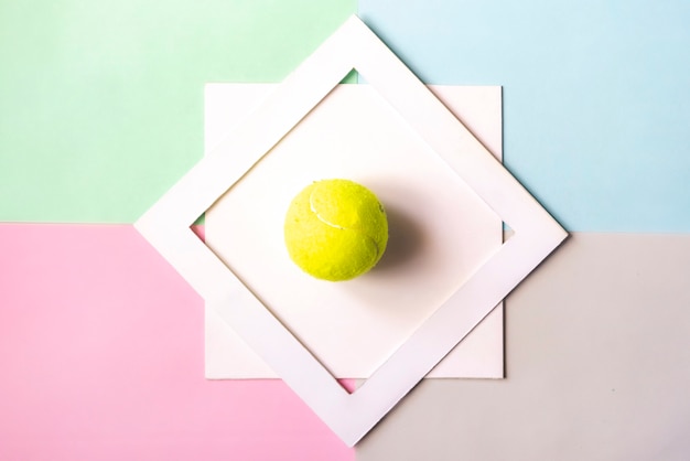 Disposizione creativa del piano con il bal di tennis isolato nel telaio bianco sul fondo di colore, concetto creativo f di idea