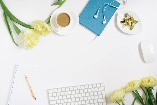 Creative flat layout of the desktop stationery keyboard headphones on a white background