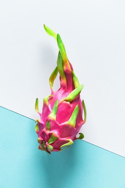 Creative flat layout with dragonfruit (pitaya or pitahaya) on two tone double color paper, white and blue. Top view of the whole fresh ripe healthy exotic fruit.