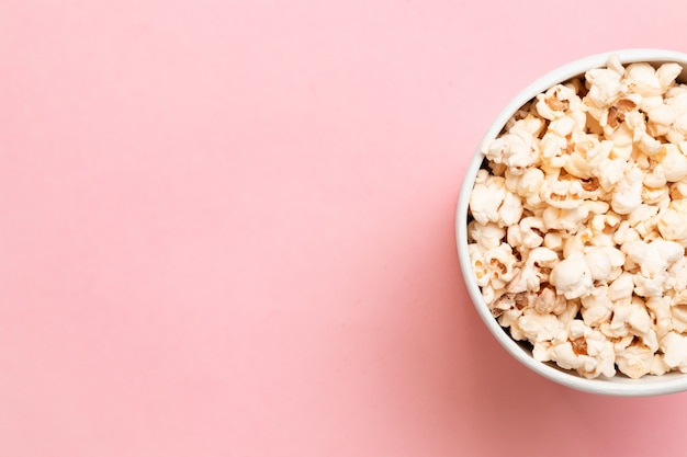 Creative food composition of popcorn in paper bag on pink background top view copy space