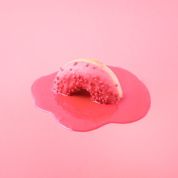 Креативная концепция питания. Розовый пончик тает на розовом фоне.