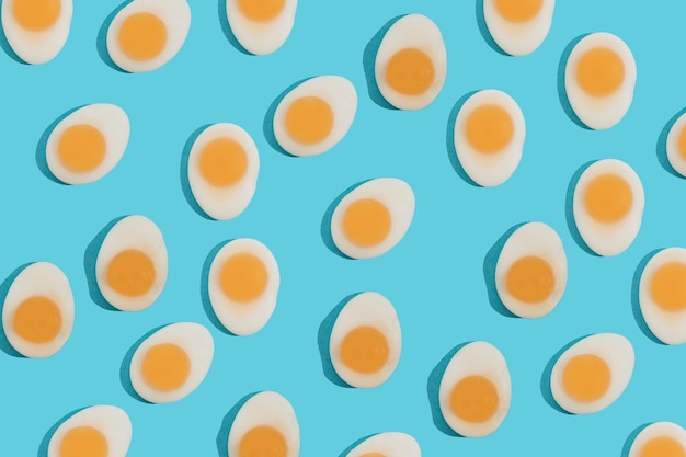 Foto concetto di cibo creativo con molte caramelle gommose a forma di uovo fritto a forma di su sfondo blu colazione mattutina vista dall'alto motivo senza cuciture stile minimal piatto blocco colore