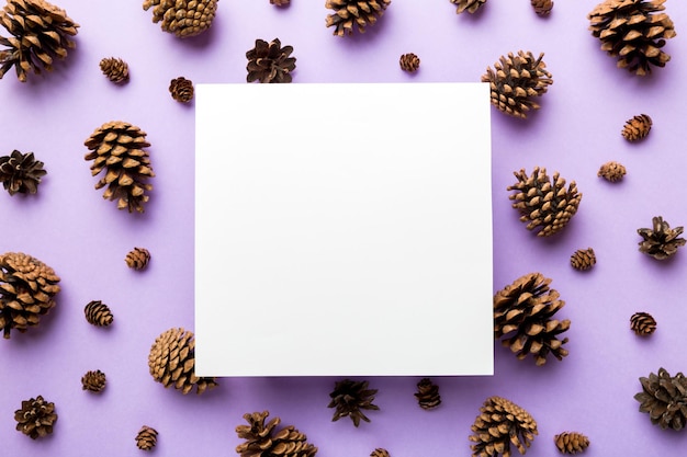 Creative frame made of christmas pine cones with square paper blank xmas and new year theme flat lay top view copy space