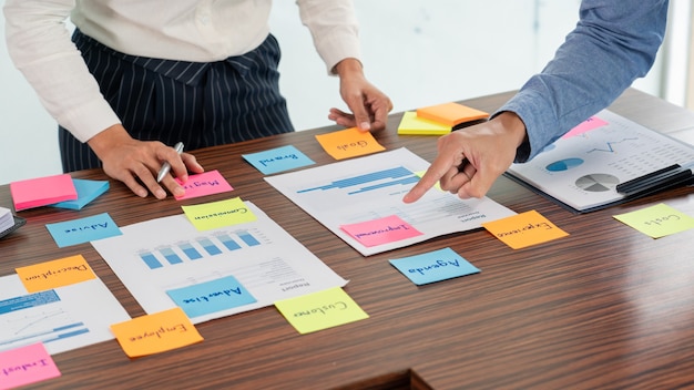 Photo creative group of business people brainstorming use sticky notes picking to share idea on table decision choosing concept for developing plan in business conference room.