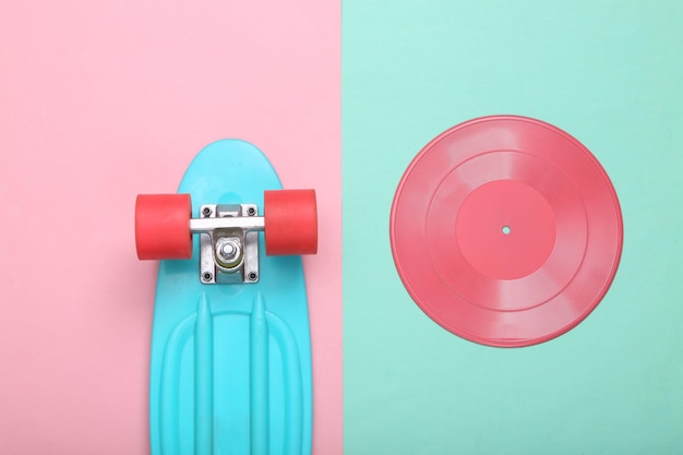 Creative hipster layout Pink vinyl record and penny board on mint blue background Minimalism Flat lay Top view