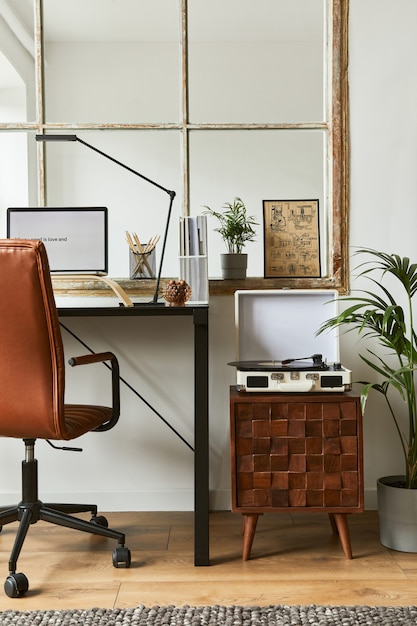 Creative home office composition of modern masculine interior
design with black industrial desk, brown leather armchair, laptop,
vintage record player and stylish personal accessories.
template.