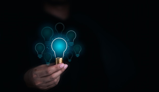 Creative idea management solution innovation knowledge technology and inspiration concept Glowing blue light bulbs graphics with blank space inside in human hand on dark background