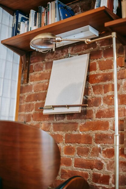 Photo creative interior of stylish room with bookshelves and clear paper for painting hanging on brick