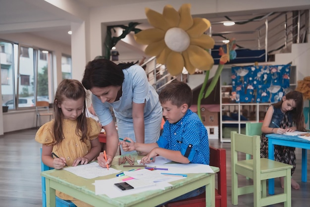 Creative kids during an art class in a daycare center or
elementary school classroom drawing with female teacher