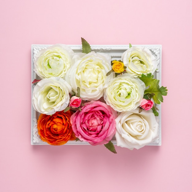 Photo creative layout of beautiful rose flowers in frame on pink surface.