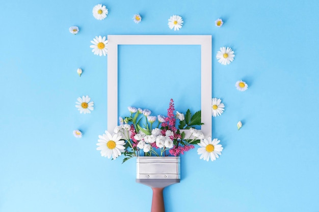 Creative layout of both brush and flowers on a blue background Floral composition