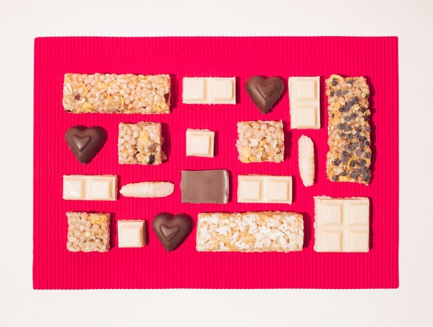 Creative layout from a chocolate and energy candies on a red background Love and health concept Flat lay frame