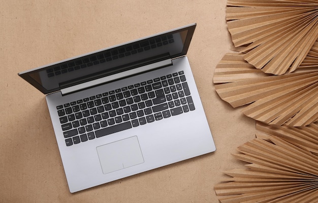 Creative layout Laptop and palm leaves on beige background Flat lay