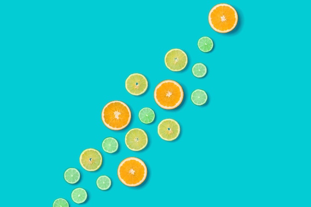 Creative layout made of colorful tropical fruits isolated on\
blue background minimal summer concept citrus fruit pattern pop art\
flat lay top view orange lime lemon slices background