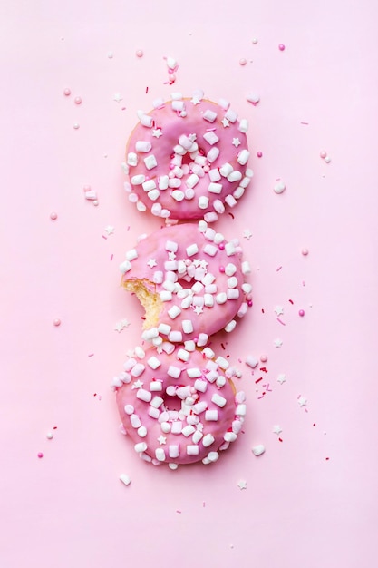 ピンクのドーナツを一列に並べたクリエイティブなレイアウト。食品のコンセプト。