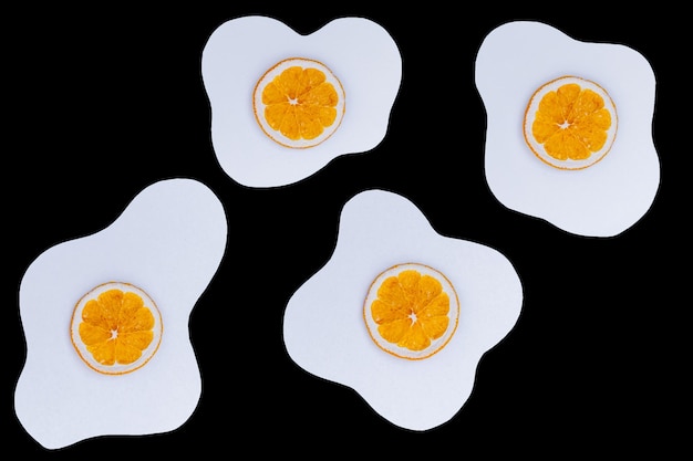 Creative layout made of scrambled eggs with circles of dried orange instead of yolk on a black background