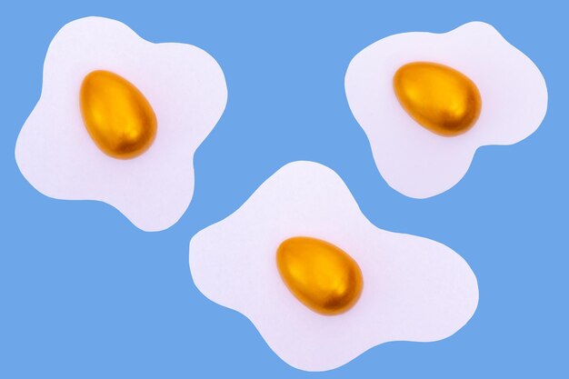 Creative layout made of scrambled eggs with decorated golden Easter eggs on a blue background