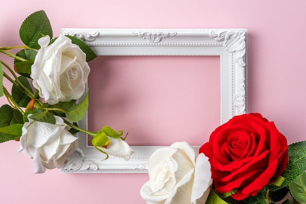 Creative layout made with flowers and white frame on pink background.