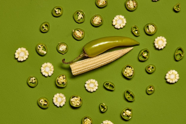 사진 녹색 배경에 있는 신선한 아름다운 칠리 페퍼와 미니 옥수수의 창의적인 레이아웃 최소 음식 개념