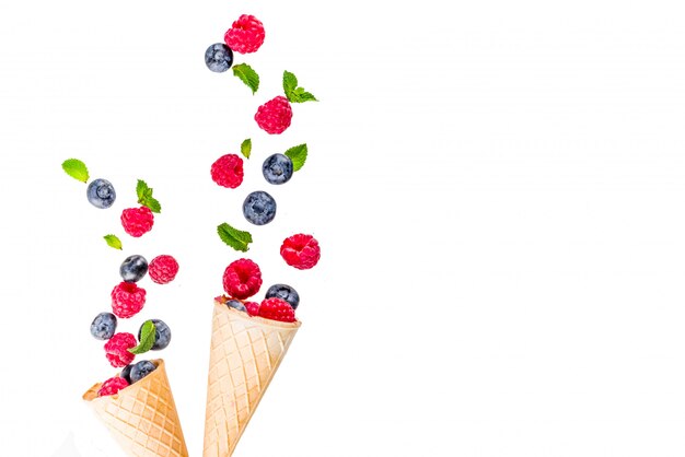 Creative layout with raspberry and blueberry with waffle ice cream cones, simple pattern aboveries