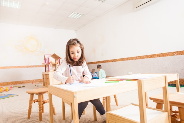 Creative little girl drawing picture with blue pencils