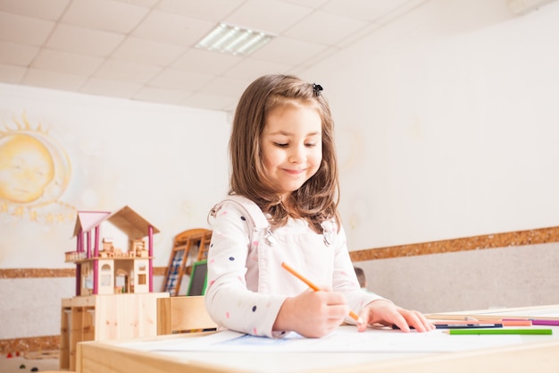 Creative little girl drawing picture with blue pencils