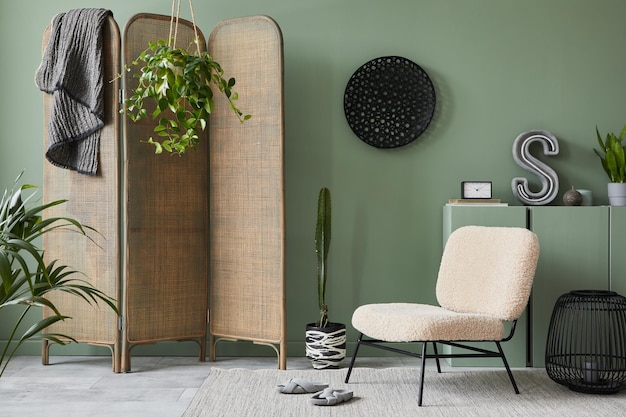 Creative living room interior composition with frotte armchair folding screen wooden commode and modern home accessories Sage green wall Template Copy space Real photo