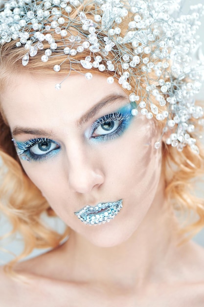 Creative makeup and beauty theme: a young girl with blue winter makeup on white background in Studio