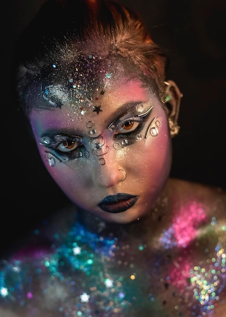 Creative makeup of a girl with rhinestones and piercing