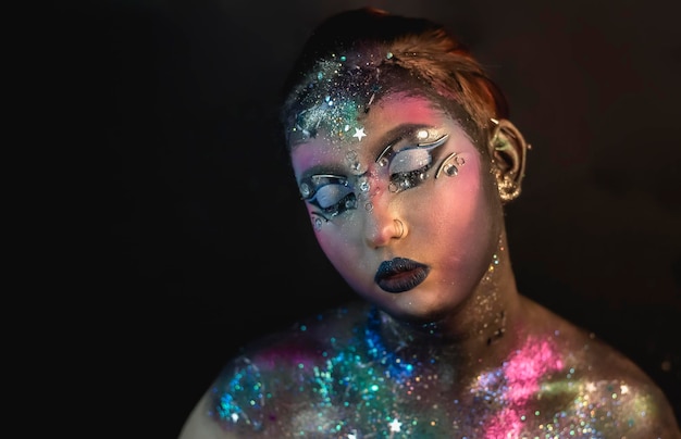 Creative makeup of a girl with rhinestones and piercing