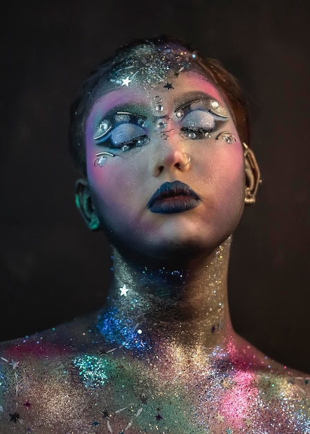 Creative makeup of a girl with rhinestones and piercing