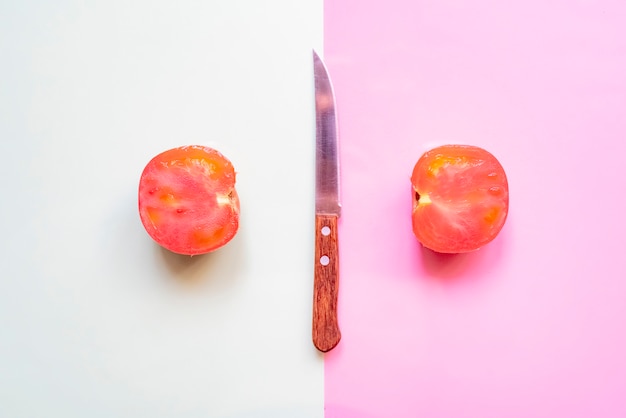 Disposizione minimalista creativa del pomodoro crudo fresco sul fondo molle di colore con il coltello f