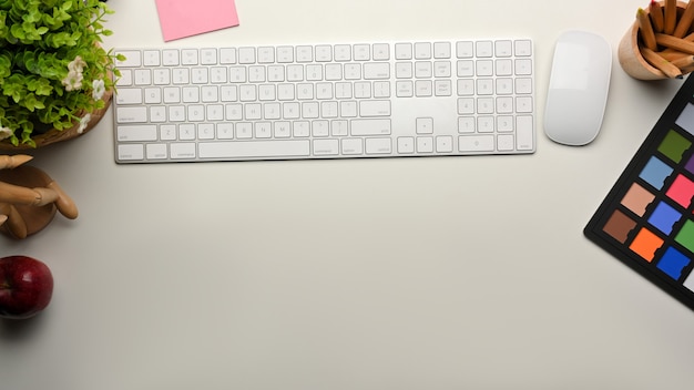 Creative mock up scene workspace with computer keyboard, mouse, paint tools and copy space on the table