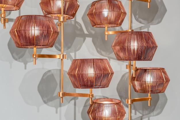 Creative modern chandelier with geometric shaped lampshade and copper details hanging against white wall