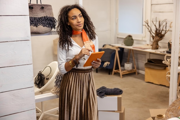 Creative mood. Young woman with a tablet in hands looking busy and thoughtful