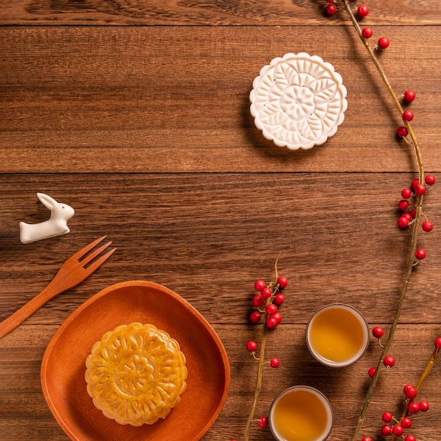 創造的な月餅月餅テーブルデザイン木製の背景にティーカップと中国の伝統的なペストリー中秋節コンセプト上面図フラットレイ