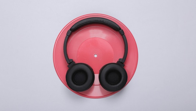 Creative music layout Pink vinyl record and headphones on gray background Minimalism Flat lay Top view