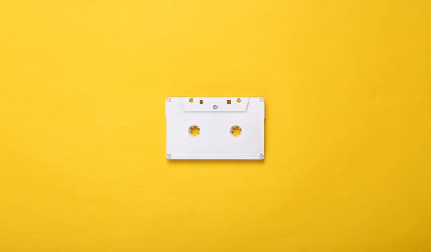 Creative music layout white retro audio cassette on yellow\
background pastel color trend minimalism concept art modern still\
life flat lay top view