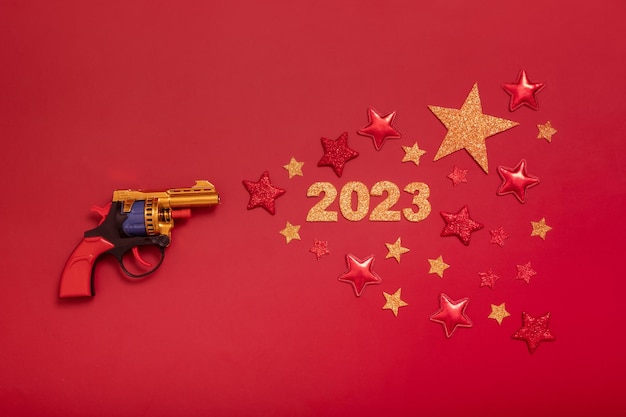 Creative New Year flat lay concept 2023 numbers with stars fly out of a toy gun