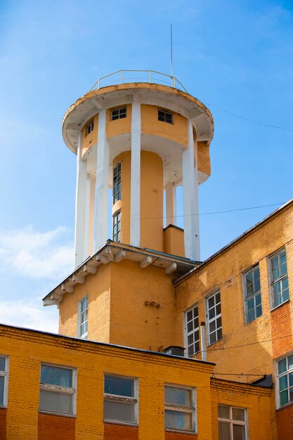 Creative old building with a tower against the background of the evening skyOld factory