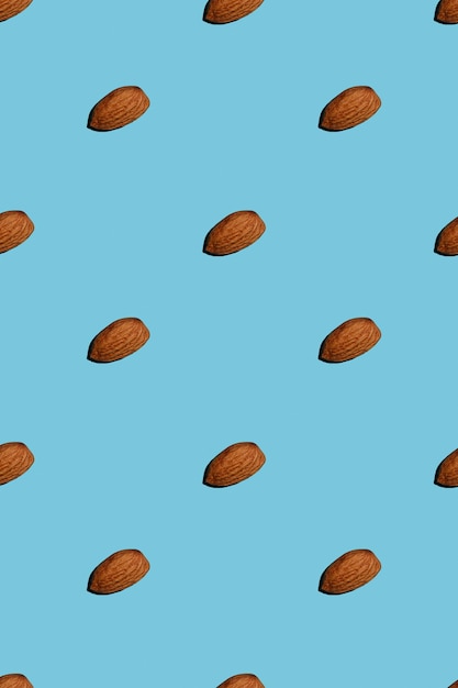 Creative pattern of almond nut on blue isolated background.