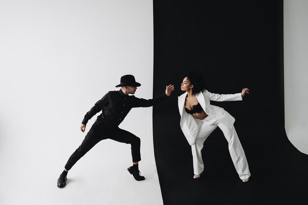 Creative photo of european man in black suit and young african american woman with curly hair on bla