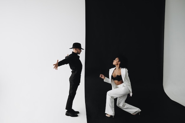 Creative photo of european man in black suit and young african american woman with curly hair on bla