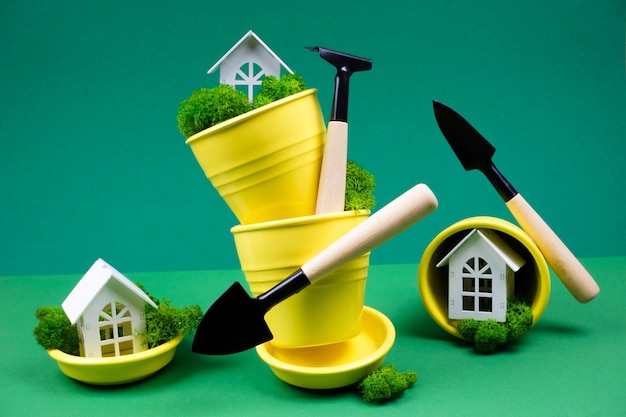 노란색 화분과 정원 도구가 있는 녹색 배경의 창의적인 사진