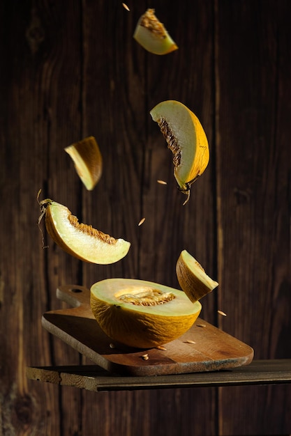 Creative photo of melon in flight, pieces of melon on a dark wooden background. photo of melon