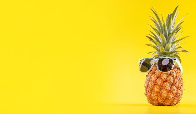 Creative pineapple looking up with sunglasses and shell isolated on yellow background summer vacation beach idea design pattern copy space close up