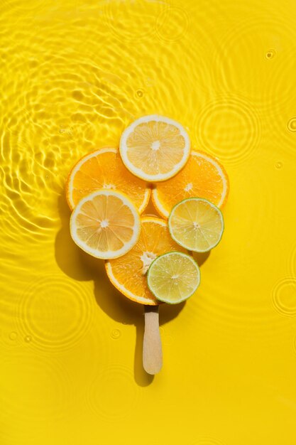 Premium Photo | Creative popsicle made from citrus fruit slices in yellow  water background with concentric circles and ripples refreshing summer  dessert concept