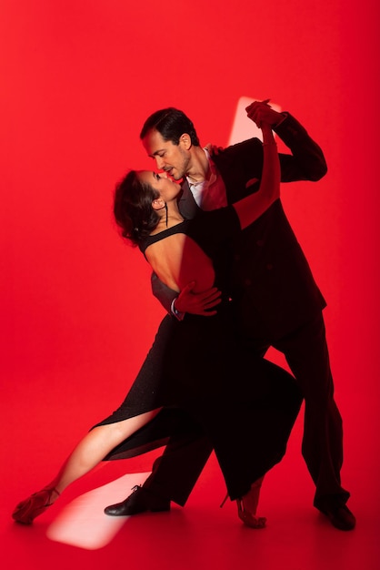 Creative portrait of tango dancers couple in dancing movement highlighted by a strip of light