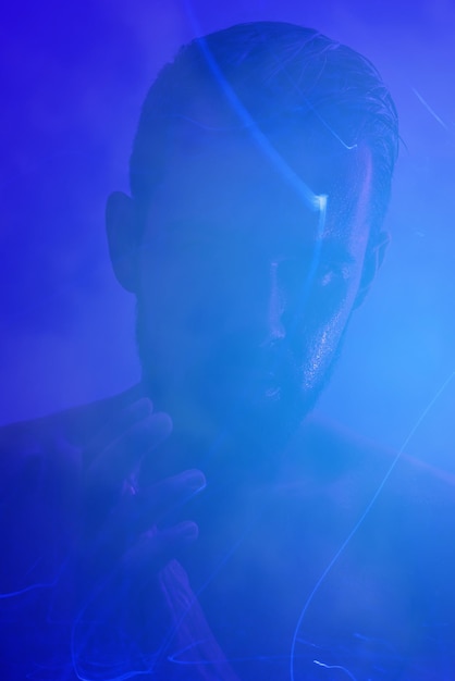 Creative portrait of young handsome man with mist and blue light